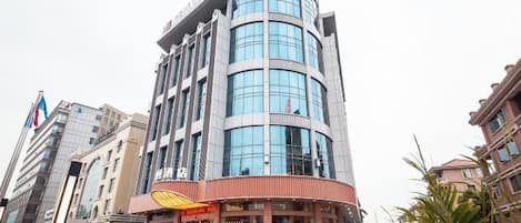 A multi-story hotel with a curved facade, a visible restaurant at the ground level, and a parking area in front.