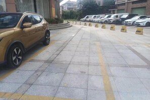 A parking area with a yellow line marking, a yellow bollard, and a yellow car parked on the left. - Weisidun Hotel (Dongguan)