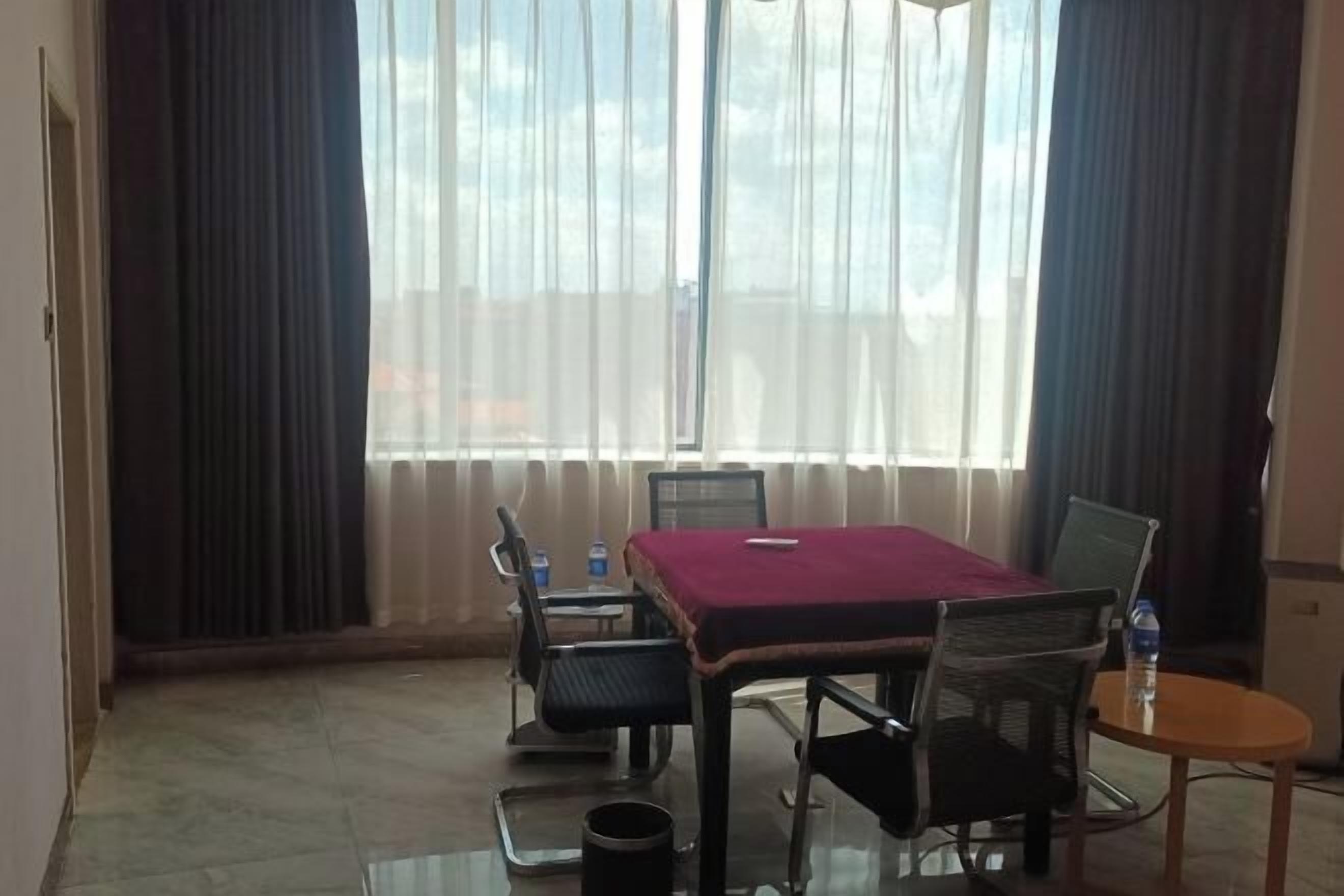 A conference room with a glass table, four chairs, a small table with a laptop, and a water bottle on the side.
