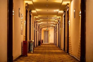 Un pasillo de hotel con puertas a ambos lados, piso alfombrado e iluminación en el techo.