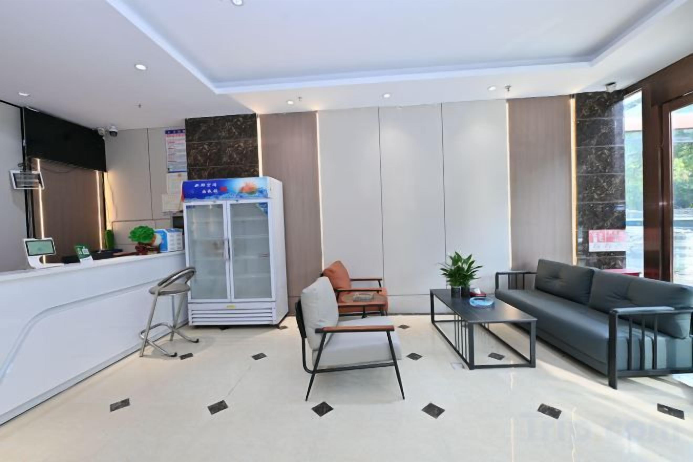 A modern hotel lobby with a reception desk, seating area, and a refrigerator.
