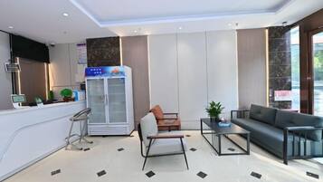 Eine moderne Hotelhalle mit einer Rezeption, einer Sitzgelegenheit und einem Kühlschrank.