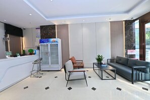 A modern hotel lobby with a reception desk, seating area, and a refrigerator. - Royal Hotel (Zhongmu)