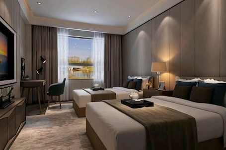 A modern hotel room with a large bed, a desk, a TV, and a view of a lake.. Royal Hotel