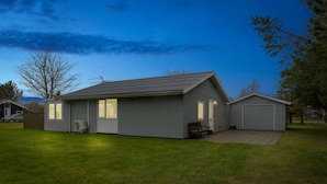Einbungalow mit Garage, überdachter Terrasse und Rasen.