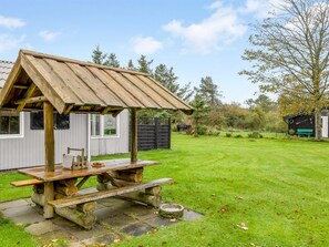 Une structure rustique en bois, dotée d’un toit en pente, d’une table de pique-nique et d’un escalier en pierre menant à l’intérieur.