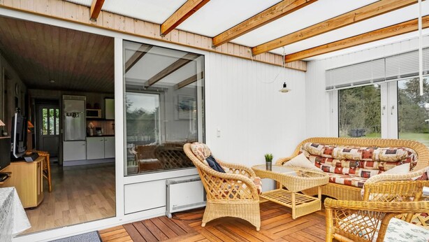 Ein modernes Interieur mit Holzboden, großen Glasüren, die in eine Küche führen, Korbmöbeln und einem Fischgrätparkett.