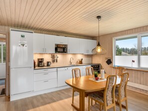 Eine moderne Küche mit weißen Schränken, einem Holzespeisetisch und einem großen Fenster.