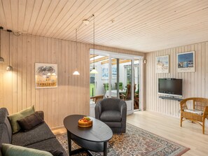 Ein modernes Wohnzimmer mit Holzboden, einem Fernseher und einem Essbereich mit Tisch und Stühlen.