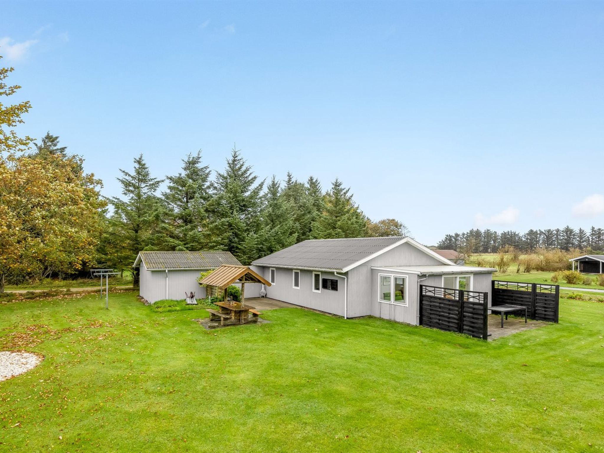 A residential property with a large lawn, a detached garage, and a fenced backyard.