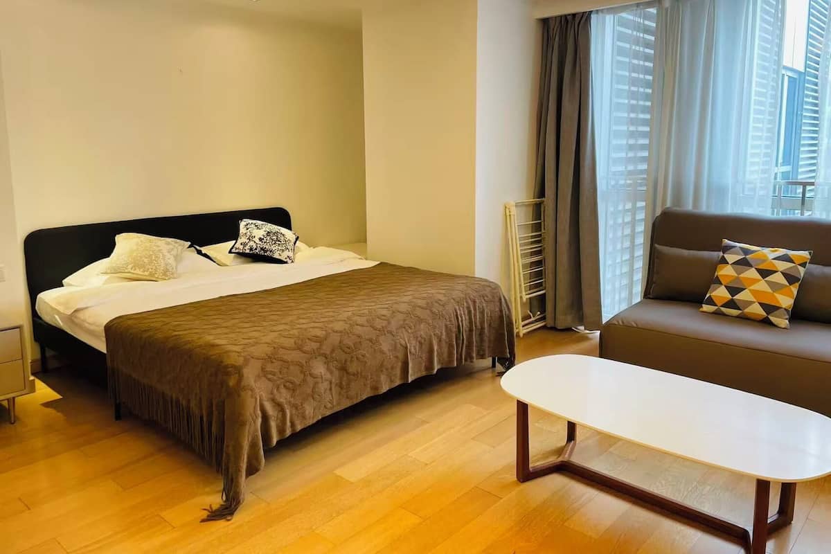 Une chambre d’hôtel avec un lit, un canapé, une table basse et une fenêtre avec des rideaux.