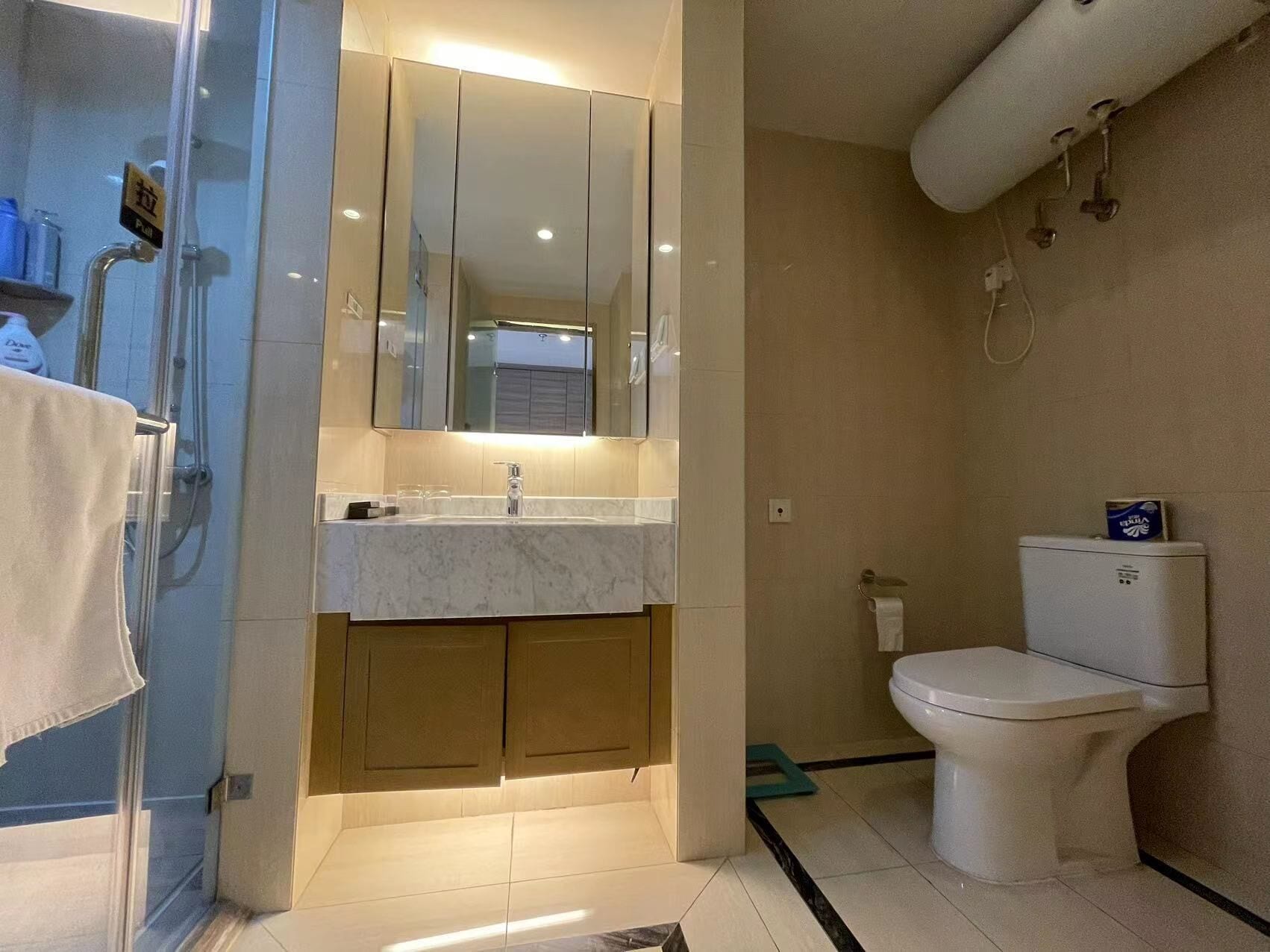 Un baño moderno con cabina de ducha de vidrio, un lavabo blanco con espejo y un inodoro.
