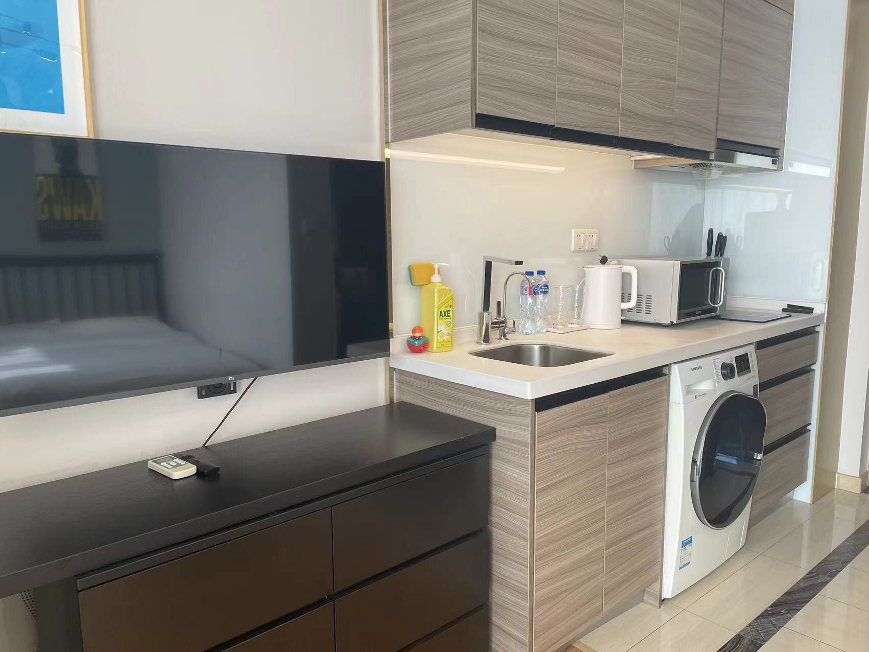 A compact kitchen with a washing machine, a microwave, and a sink.