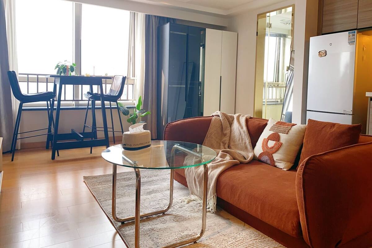Un salon moderne avec une table basse en verre, un canapé marron et un coin repas comprenant une table et des chaises.
