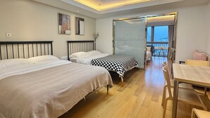 Een moderne hotelkamer met twee bedden, een eethoek en een balkon met uitzicht over de stad.