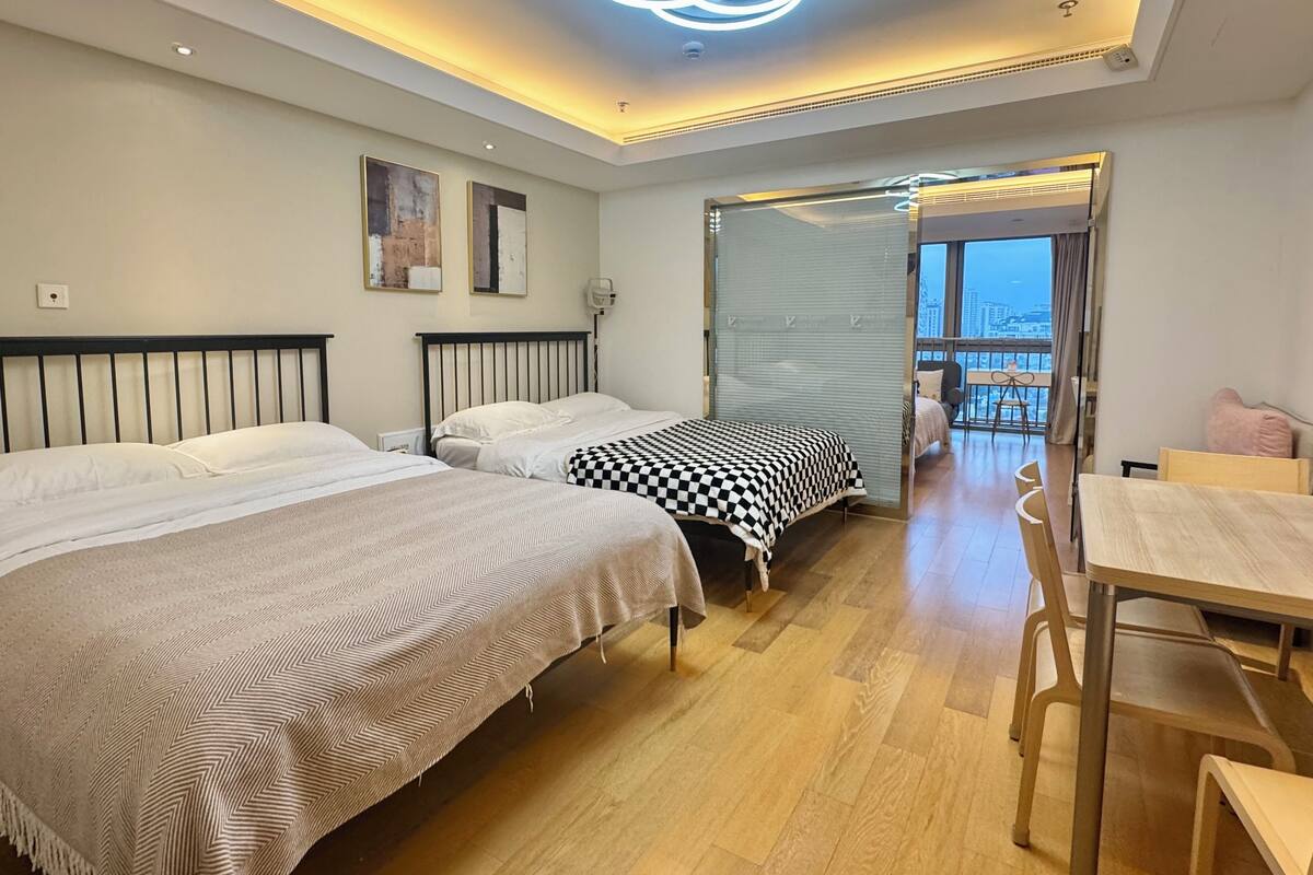 Une chambre d’hôtel moderne avec deux lits, un coin repas et un balcon offrant une vue sur la ville.
