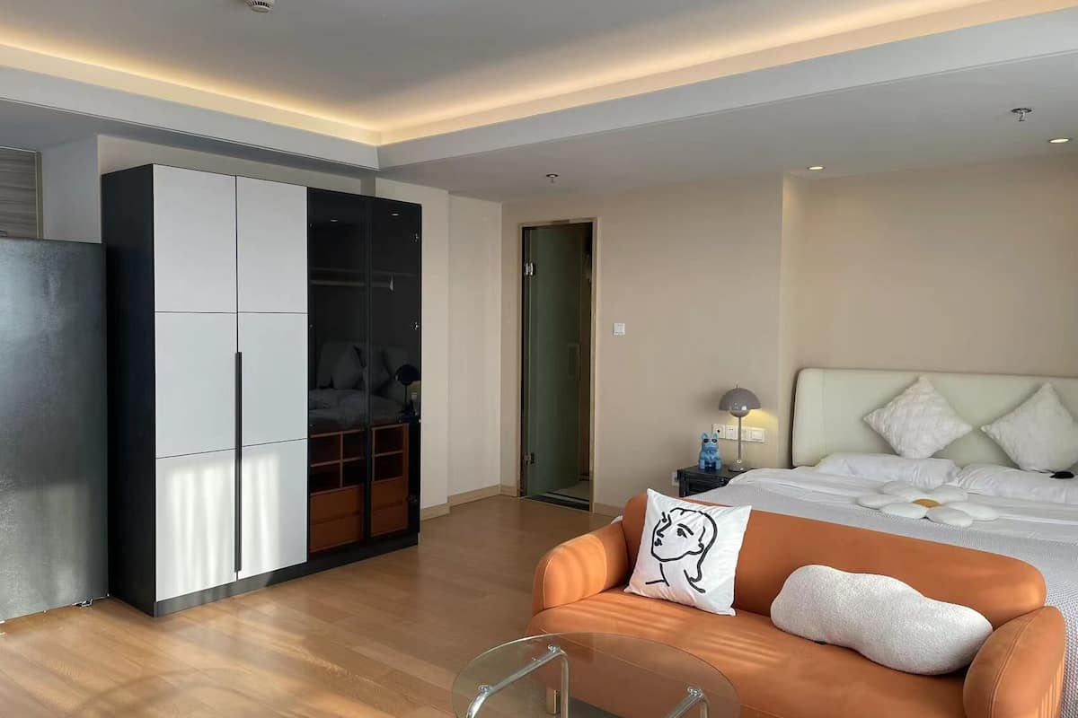 Une chambre d’hôtel moderne équipée d’un lit, d’un canapé, d’une table basse en verre et d’une armoire.