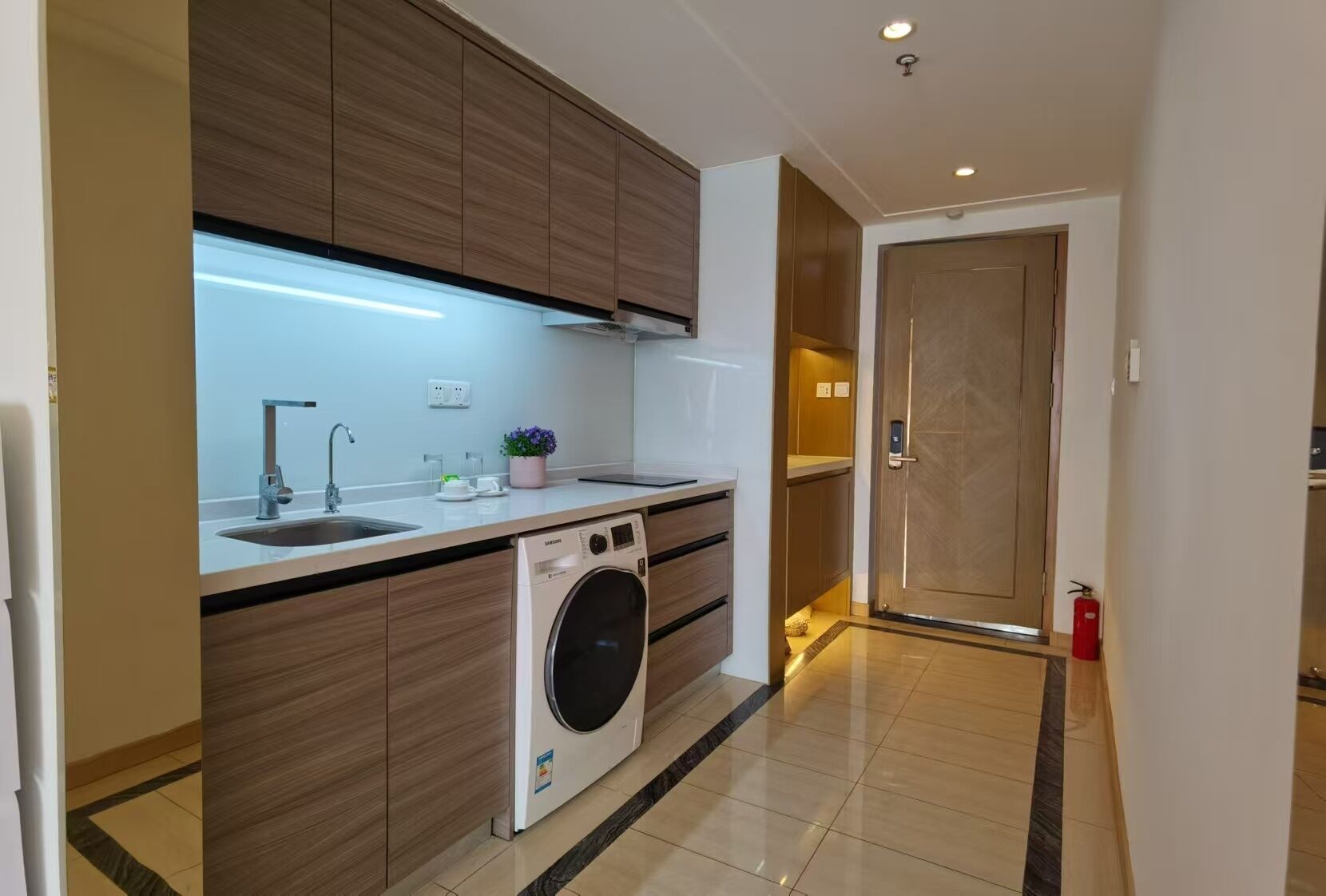 A modern kitchen with a built-in washing machine, a sink, and wooden cabinets.