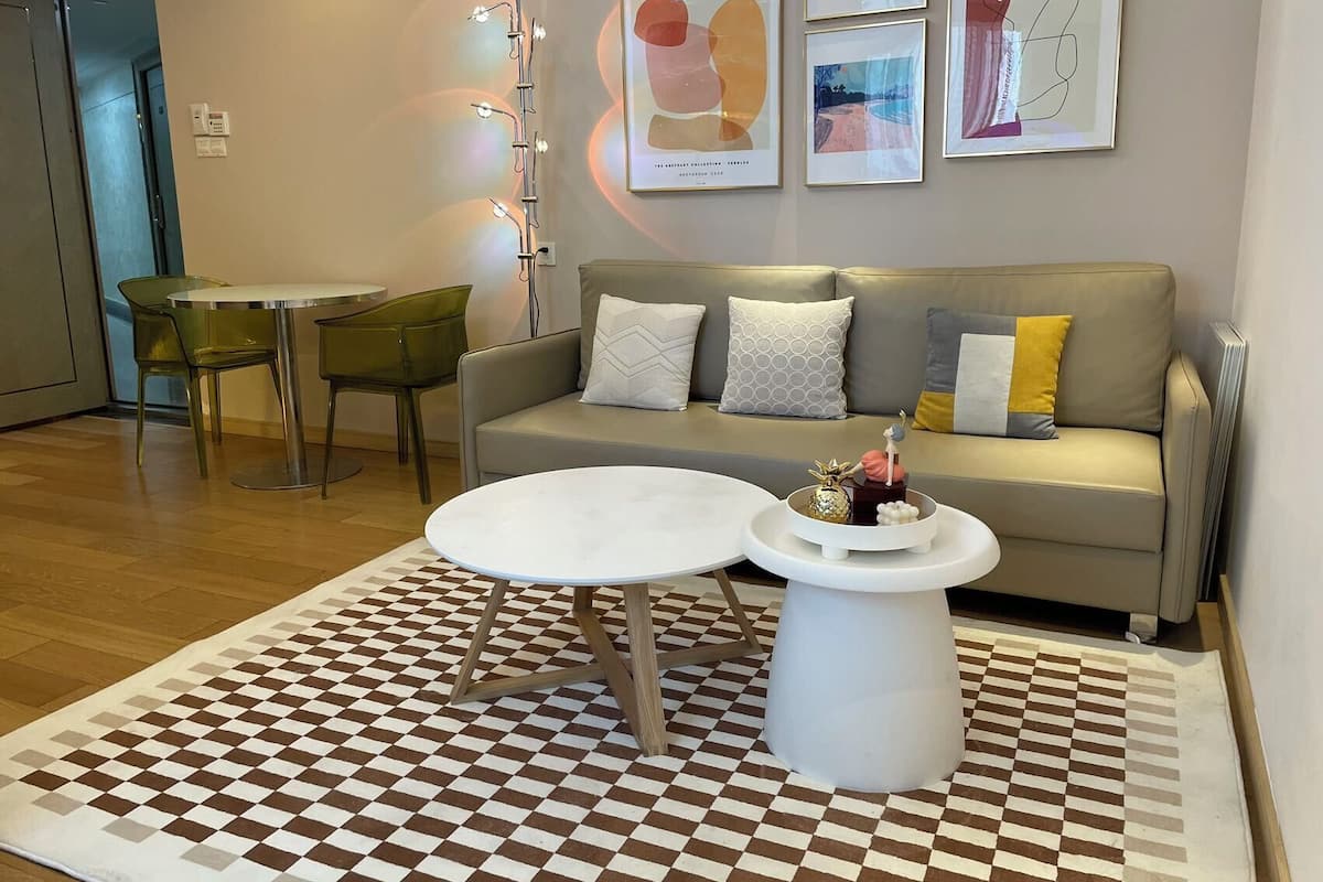 Un salon moderne avec un canapé, deux fauteuils, une table basse et un tapis à motifs.