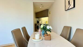 A dining area with a marble table, four chairs, a vase with flowers, and a small basket.