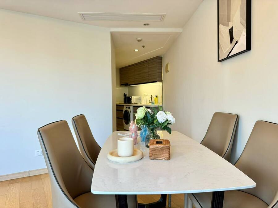 A dining area with a marble table, four chairs, a vase with flowers, and a small basket.