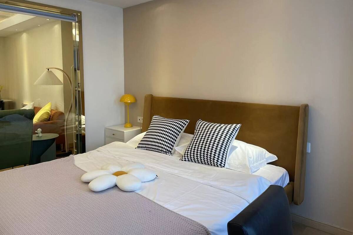 Une chambre d’hôtel avec un lit, une table de chevet, une lampe, un miroir et une vue sur l’extérieur.