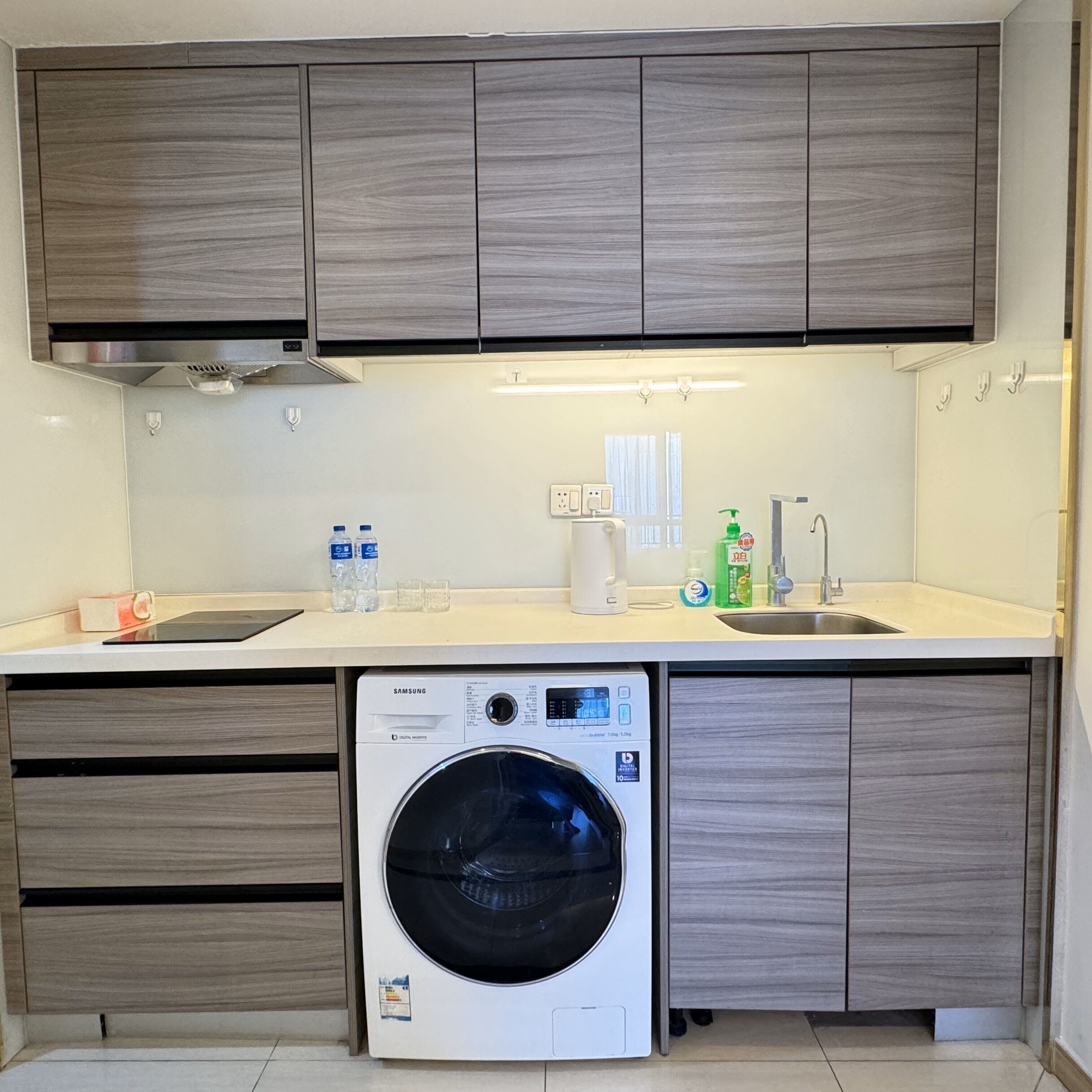 A compact kitchen with built-in appliances, including a washing machine and a sink.