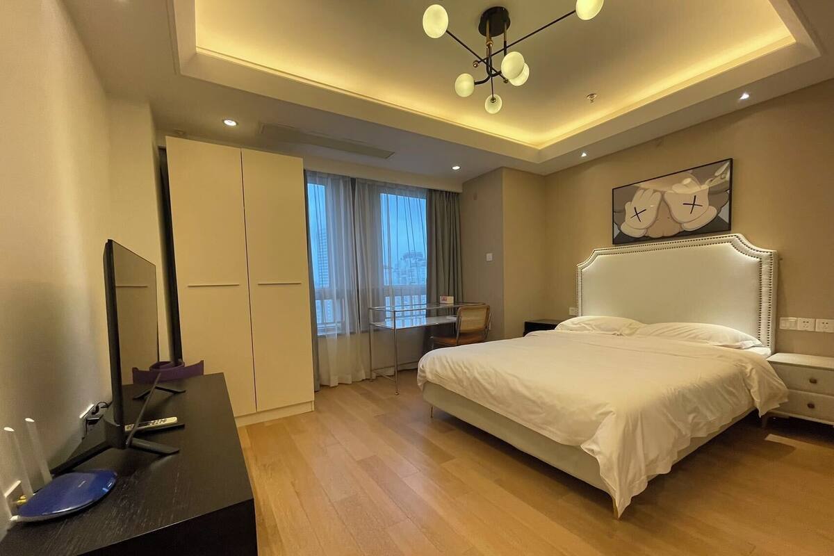 Une chambre d’hôtel moderne dotée d’un grand lit, d’un bureau avec une chaise, d’une armoire et d’un luminaire au plafond.
