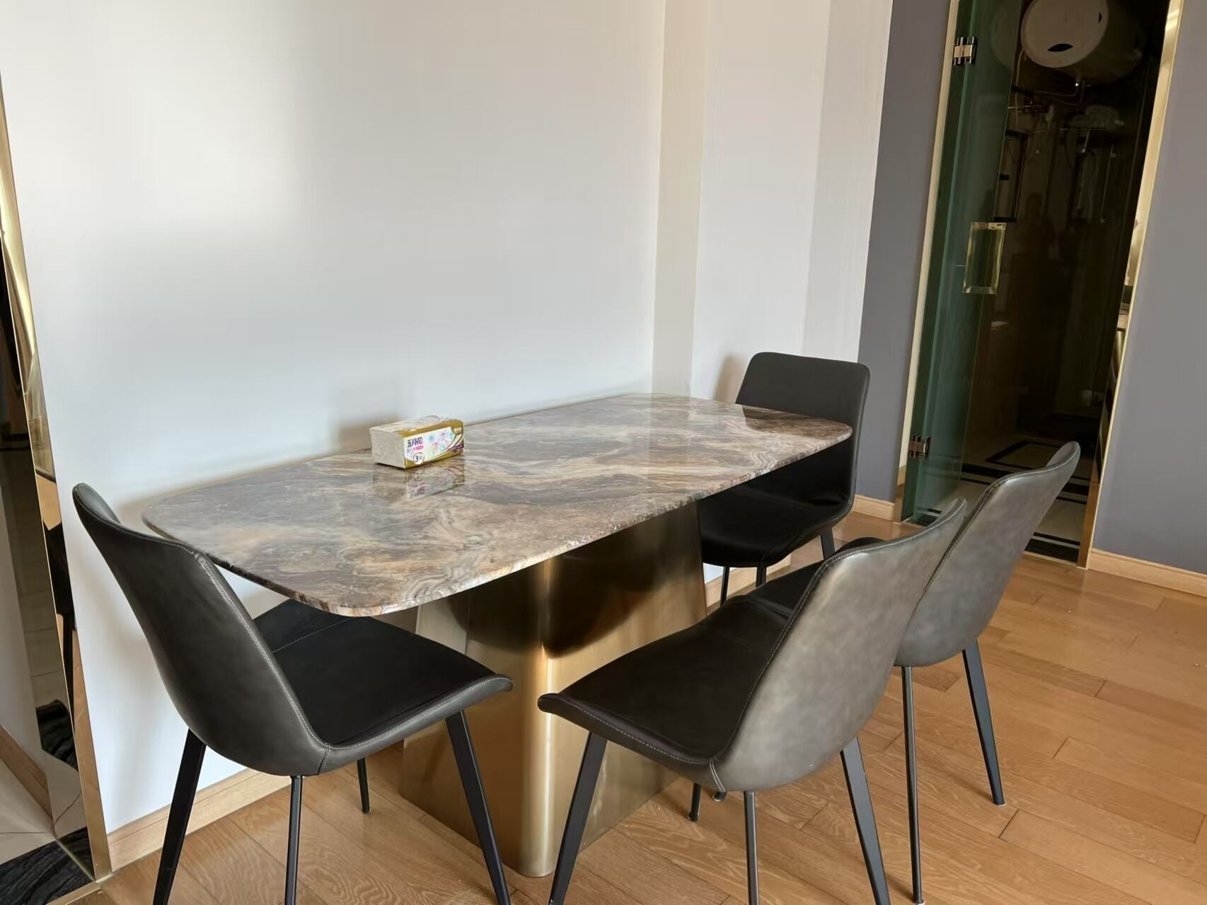 A modern dining area with a marble table and black upholstered chairs.
