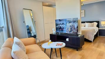 Una habitación de hotel moderna con sofá, televisión, mesita de noche y cama.