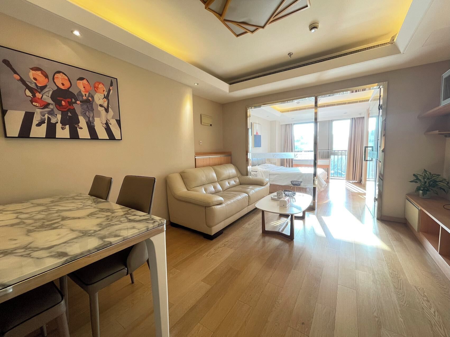 Amplia sala de estar con una mesa de comedor de mármol, un sofá de cuero y un balcón con vistas.