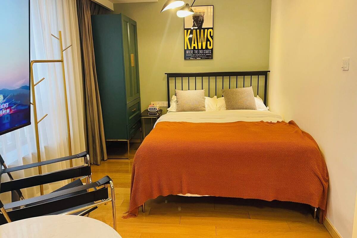 Une chambre d’hôtel avec un lit, une télévision, un bureau et une affiche au mur.