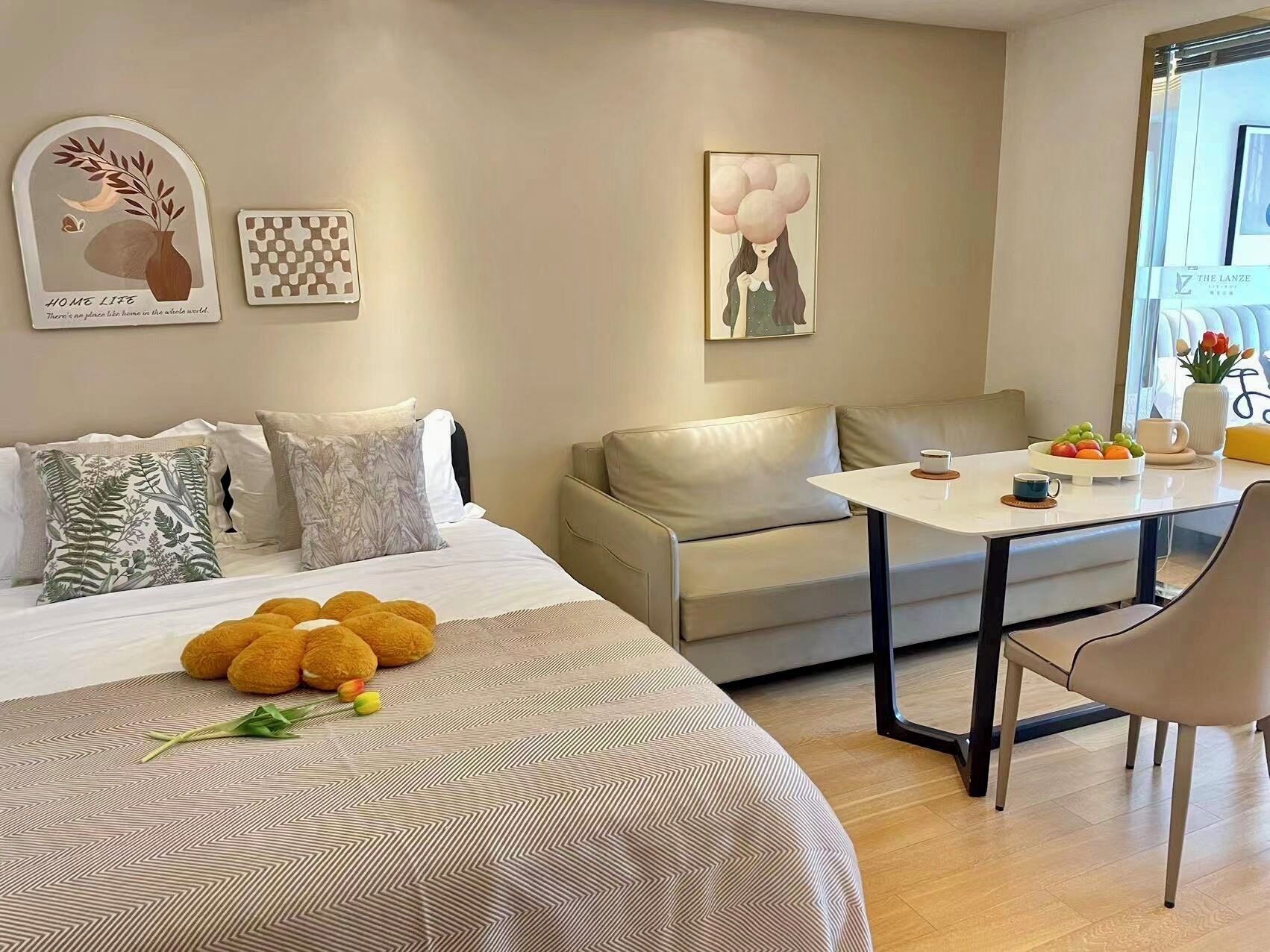 A modern hotel room with a bed, a sofa, a dining table, and a window with a view.