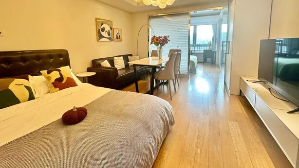 Een moderne hotelkamer met een groot bed, een zithoek, een televisie en een balkon met uitzicht.