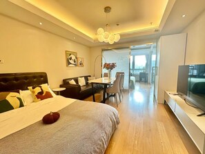Une chambre d’hôtel moderne dotée d’un grand lit, d’un coin repas, d’une télévision et d’un balcon avec vue.