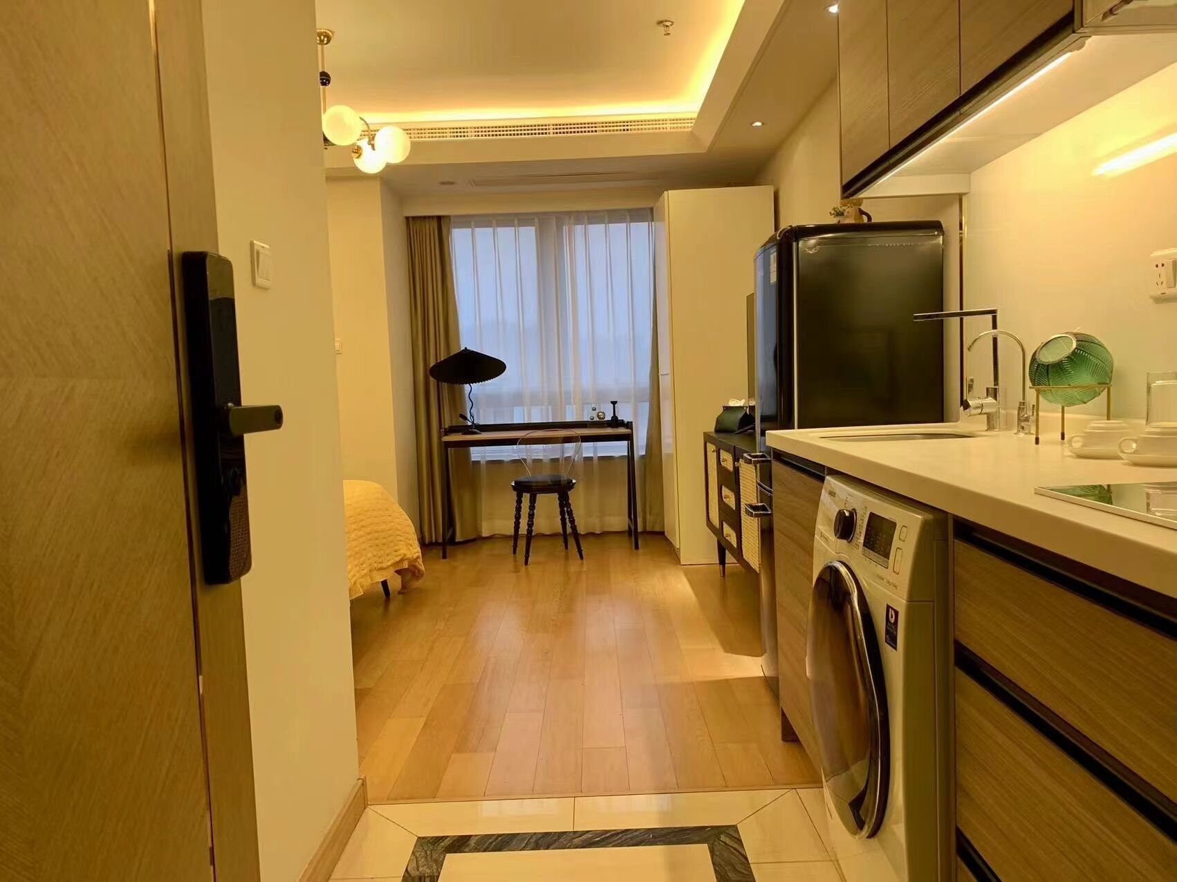 A compact kitchen with a washing machine, a refrigerator, and a dining area with a table and chairs.