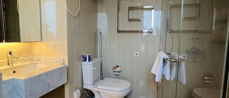 Une salle de bain moderne avec un lavabo en marbre, des toilettes, une douche en verre et un porte-serviettes.