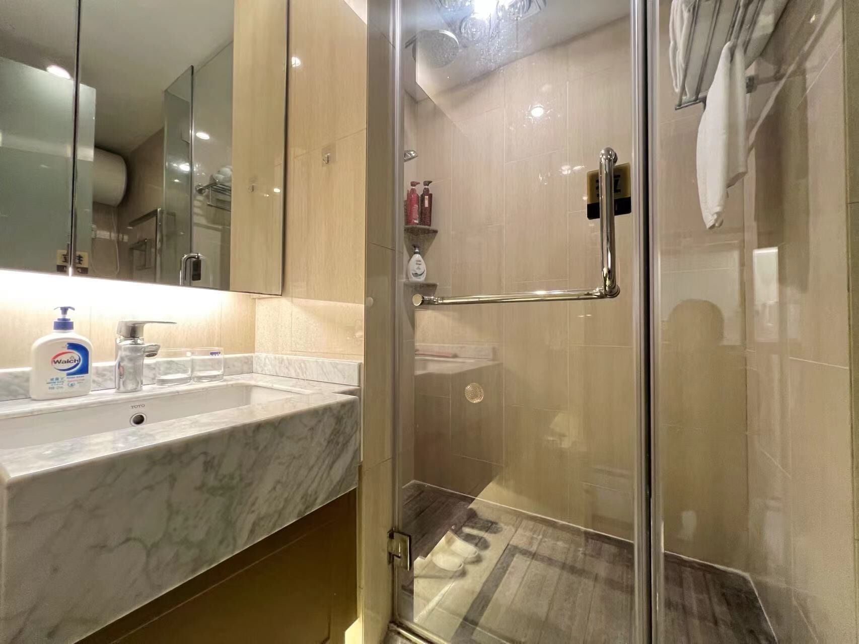 A modern bathroom with a glass shower enclosure, a marble sink, and toiletries on the counter.