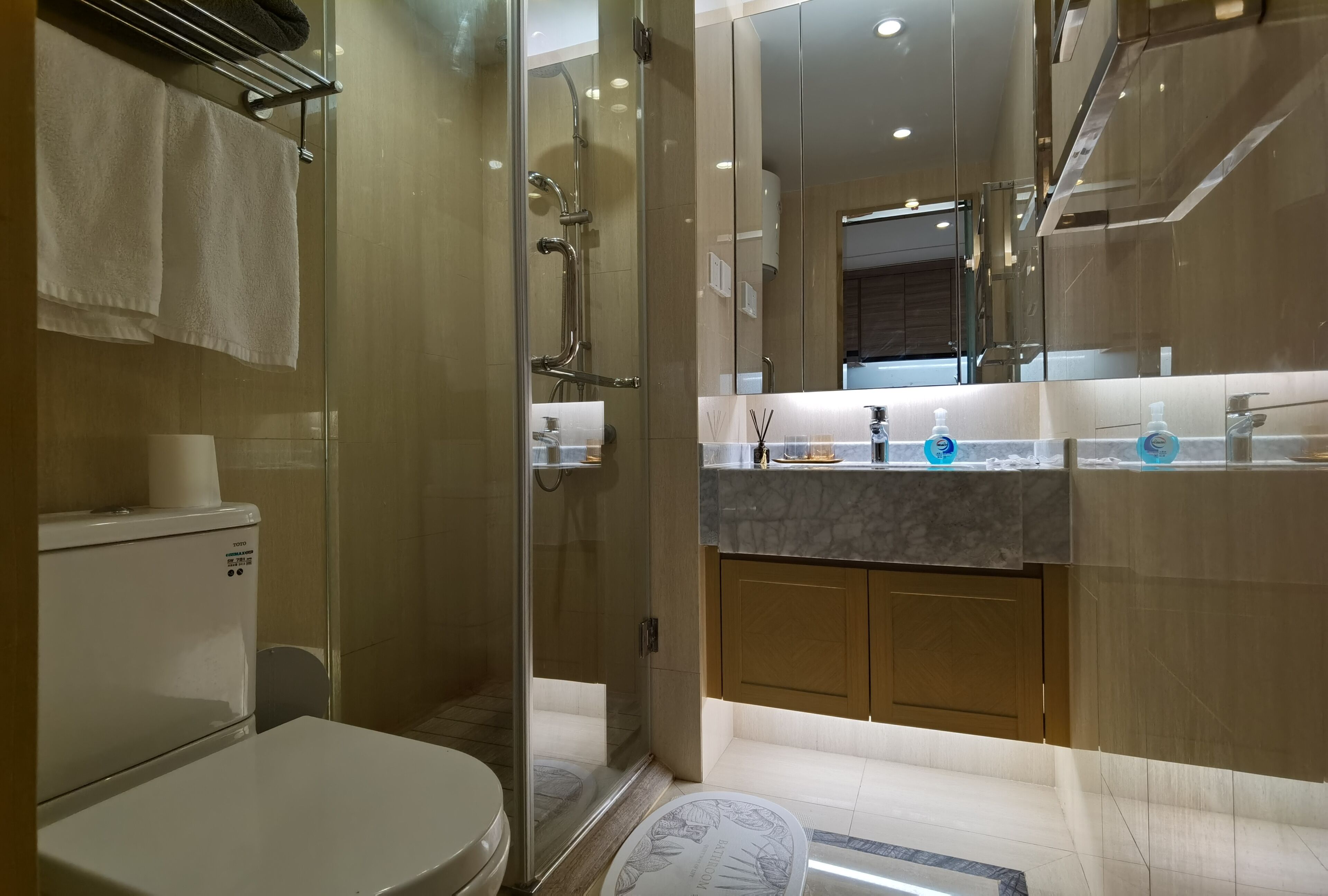 A modern bathroom with a glass-enclosed shower, a toilet, and a vanity with a mirror.