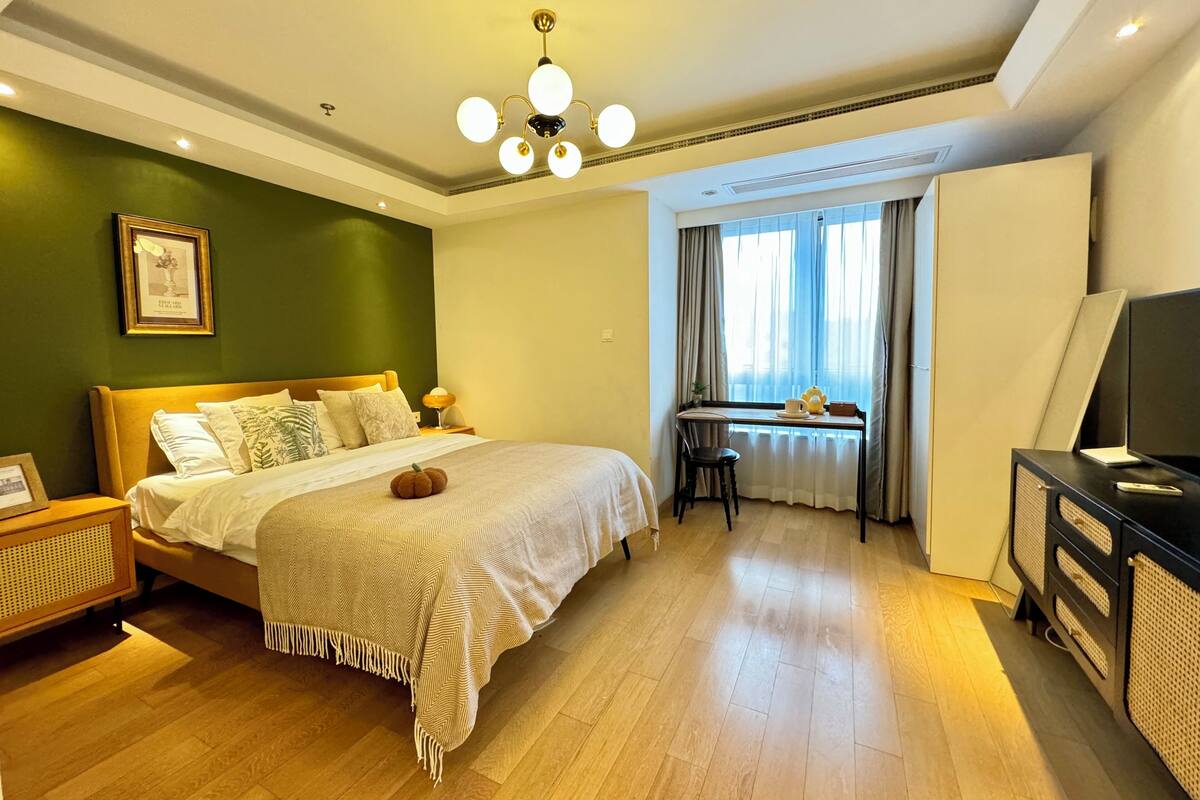 Une chambre d’hôtel avec un lit, un bureau, une télévision et une fenêtre avec des rideaux.