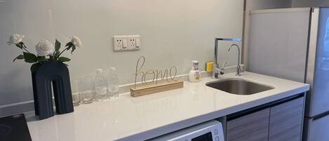A modern kitchen with a built-in washing machine, a sink, and a countertop with a vase of white roses.