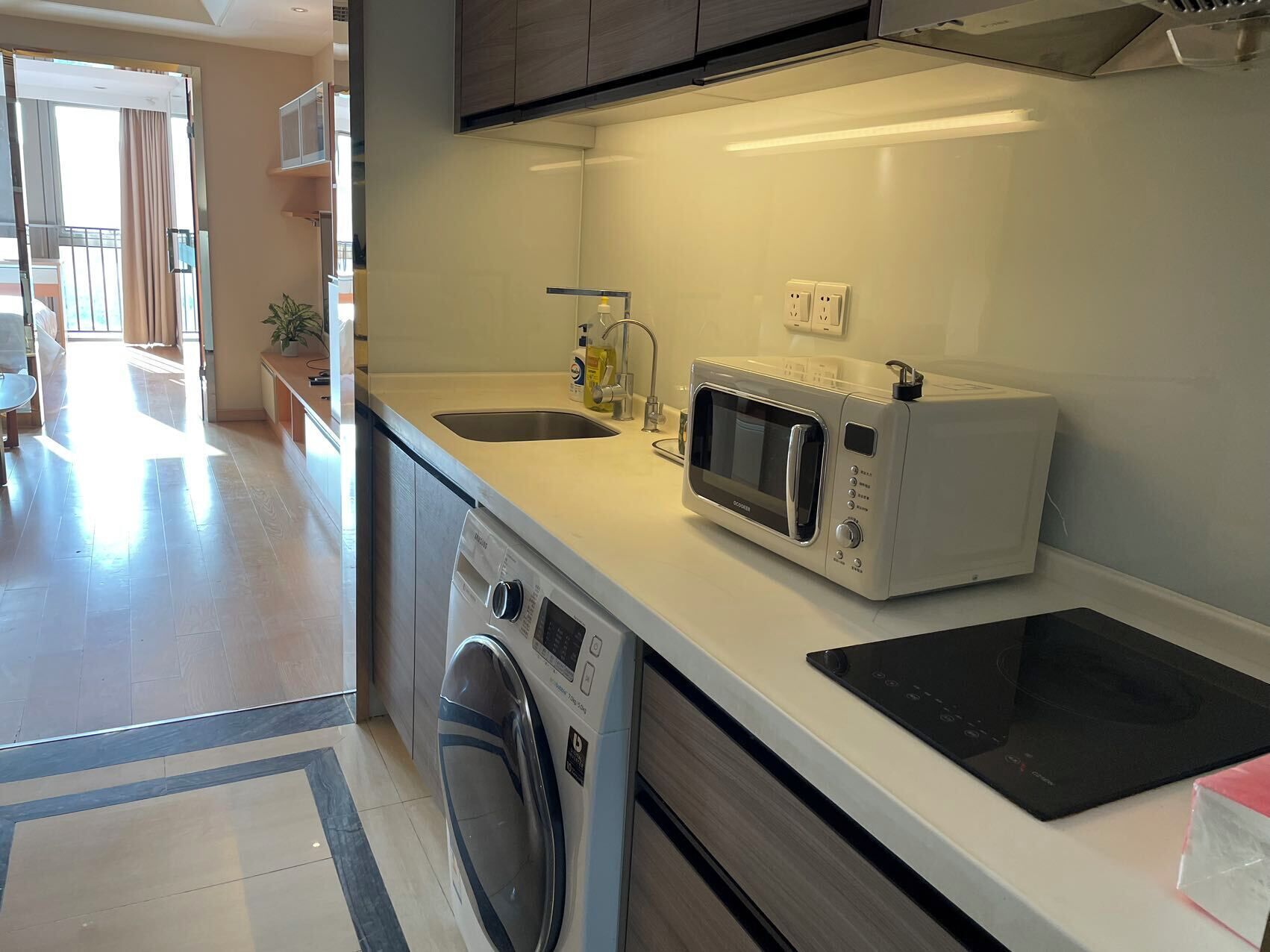 A modern kitchen with a built-in microwave, a toaster, a washing machine, and a sink.
