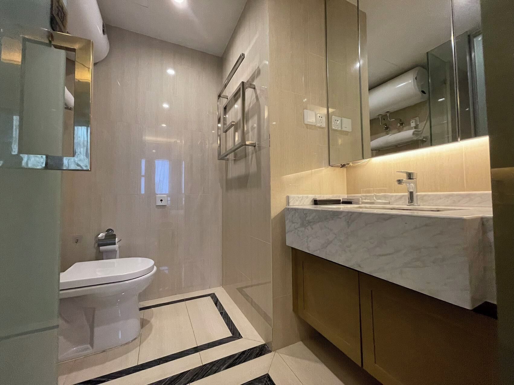 A modern bathroom with a toilet, a sink, and a mirror.