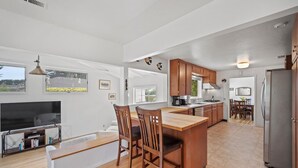 Una cocina moderna con armarios de madera, una isla central y un área de comedor con sillas.