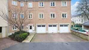 Un edificio residencial de varios pisos con fachada de ladrillo, dos puertas de garaje y un camino de acceso pavimentado.