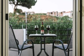 Ein Balkon mit zwei Stühlen, einem Tisch und zwei Weingläsern sowie einer Weinflasche.