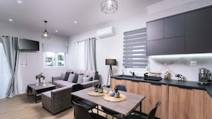 Ein modernes Wohnzimmer mit Sofa, Esstisch und Küchenzeile mit Schränken und Arbeitsplatte.