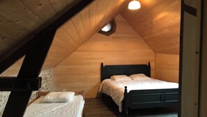 A small, cozy attic bedroom with a sloped ceiling, a single bed, and a small window. - Farm cottage (Sainte-Christine)