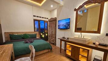 Un dormitorio con cama, televisor, aparador de madera y un espejo grande.
