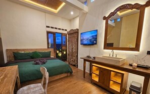A bedroom with a bed, a television, a wooden cabinet, and a large mirror. - GWK View Boutique Hotel and Serviced Residence (Jimbaran)
